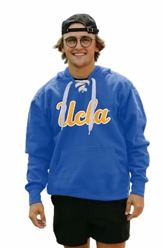 Person wearing a blue UCLA hoodie and a cap