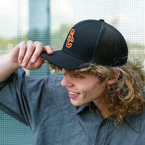 Young man wearing a black cap with a red and yellow logo